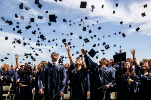 College graduates looking up as their graduation caps soar