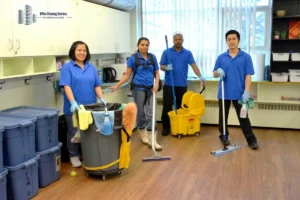 Four cleaning crew posing with equipment and smiling