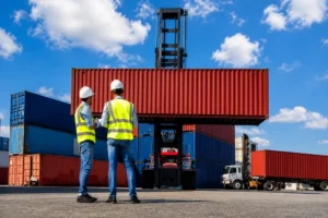 Logistics workers supervising shipping container loading operations at a commercial container yard