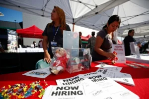 Women presenting a now hiring sign to job applicants