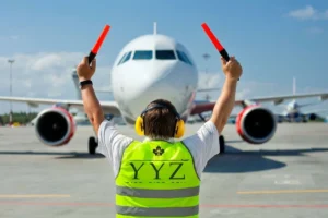 Aircraft marshaller directing an airplane to the designated parking stand.