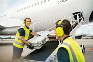 Baggage handlers loading passenger luggage into an airplane.