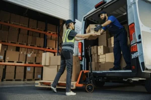 Delivery personnel handing a box to a woman from a transport van.
