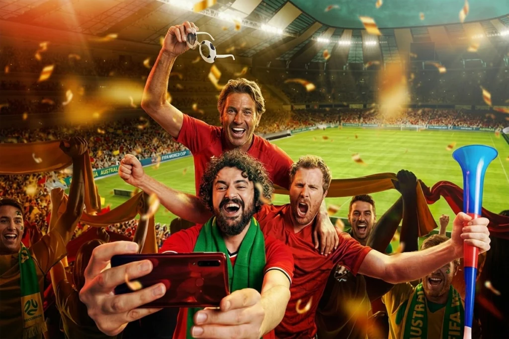 Fans taking a selfie in the stadium while watching a live football game