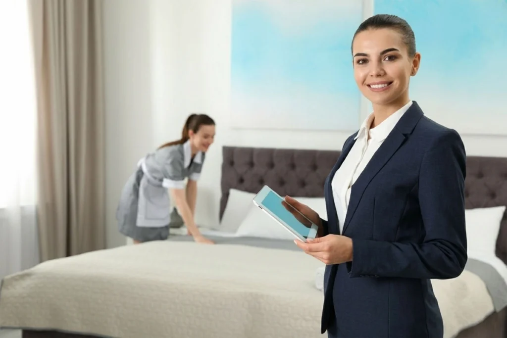 Housekeeping staff cleaning a hotel room while a supervisor conducts an inspection.