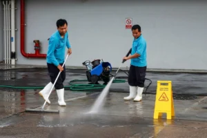 Janitorial staff cleaning the floor using brooms and scrubbing equipment.