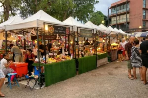 Local morning market with shoppers browsing fresh produce stalls.