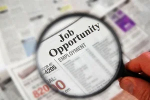 Magnifying glass highlighting job opportunities in a newspaper