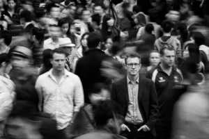 Man standing still as people walk past in soft blur