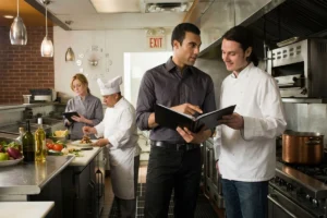 Manager and chef talking in a restaurant kitchen.