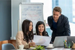 Manager reviewing paper charts with an employee during a team meeting.