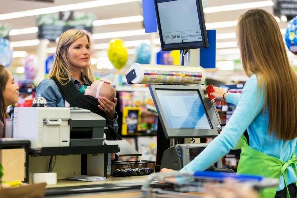 Mother with her baby waiting to complete a grocery checkout.