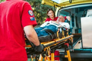 Paramedics transferring a patient into an ambulance during an emergency response.