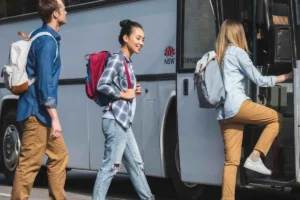 Passengers lining up to board a bus, with a woman entering first.