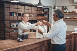 Retail staff giving a shopping bag to a customer after checkout.