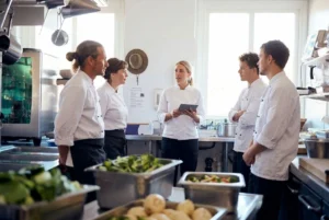 Restaurant kitchen supervisor discussing daily tasks with staff members.