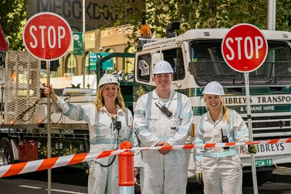 Road construction crew wearing PPE directing traffic with a stop sign.