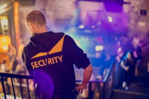 Security officer monitoring people from the top of a staircase.