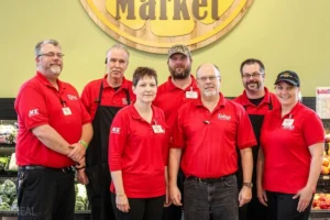 Supermarket staff smiling together in the grocery store.