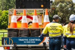Traffic controller standing beside a truck loaded with traffic control equipment.