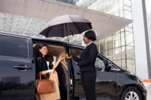 Woman stepping out of a van while a staff member provides umbrella assistance.
