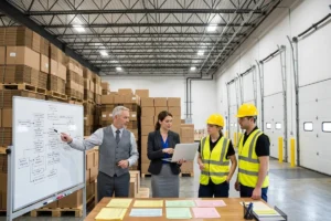 Business owner leading a meeting with managers and employees using a whiteboard.