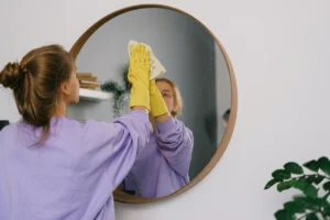 Woman cleaner wiping a mirror with a microfiber cloth.