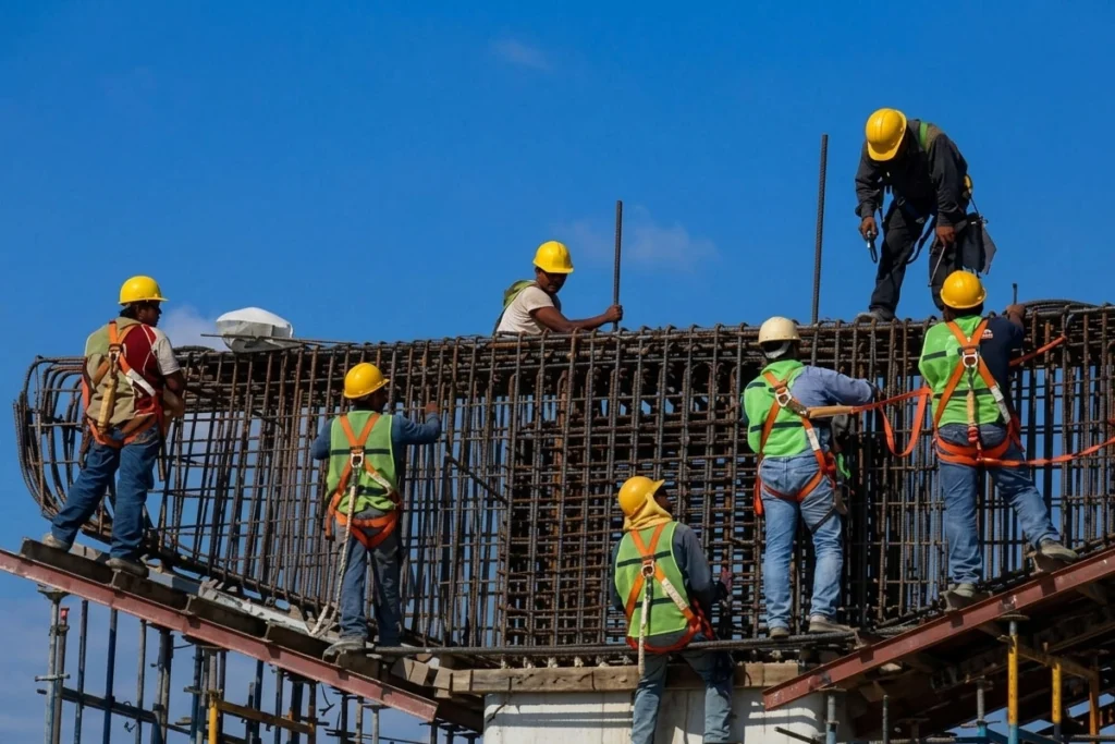 Construction crew assembling steel reinforcement for a bridge foundation.