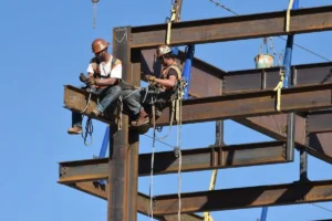 Construction workers installing steel beams on a building framework.