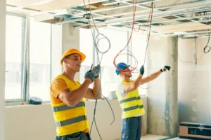 Electrician working on ceiling electrical cables.
