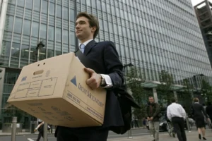 Office employee carrying a box of work files and personal belongings.