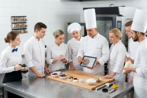 Head chef training kitchen staff during a restaurant team meeting.