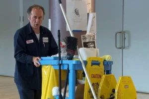 Janitor pushing a cleaning cart stocked with cleaning supplies.