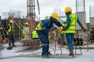 Two construction workers measuring and marking a steel beam.