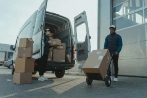 Warehouse worker unloading delivery packages with a hand trolley.