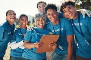 Six volunteers wearing blue shirts, smiling while standing together.