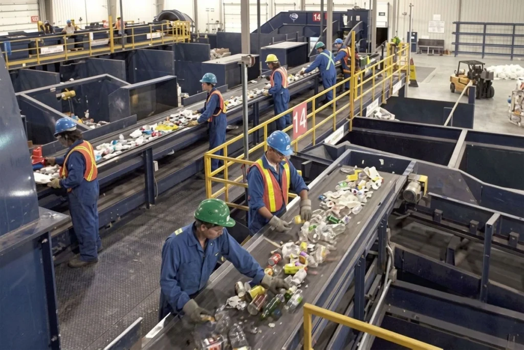 Worker wearing PPE sorting products on a conveyor belt.