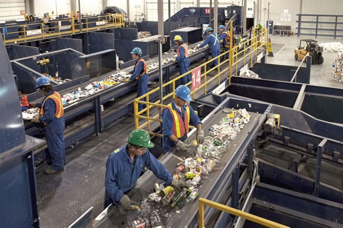 Worker wearing PPE sorting products on a conveyor belt.
